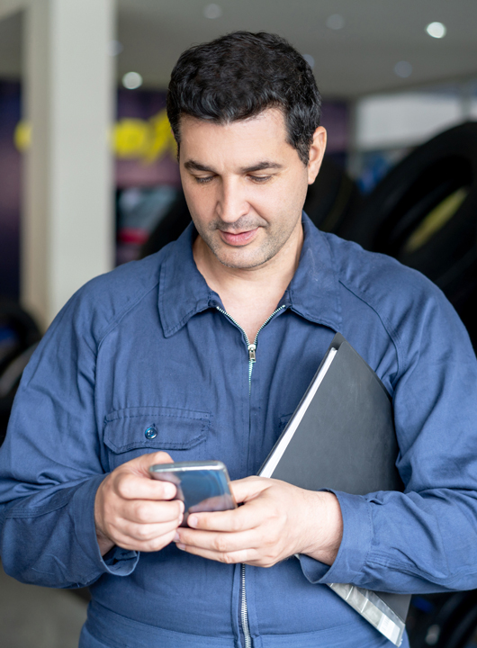 Service tech texting a customer on his cell phone in the service drive.