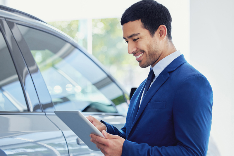 Young salesman looking at tablet inside dealership