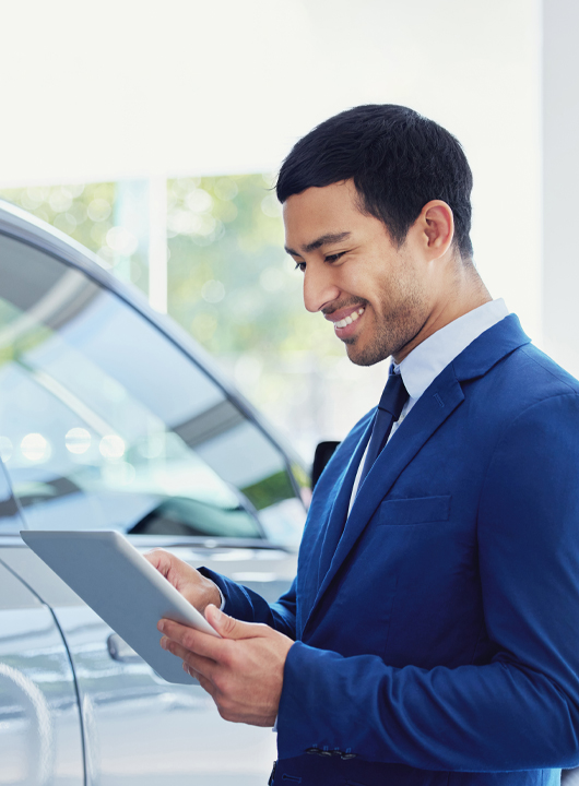 Young salesman on tablet inside dealership.